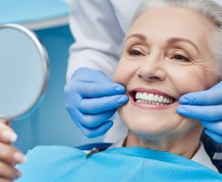 Dentist examining senior woman's teeth with mirror in modern clinic